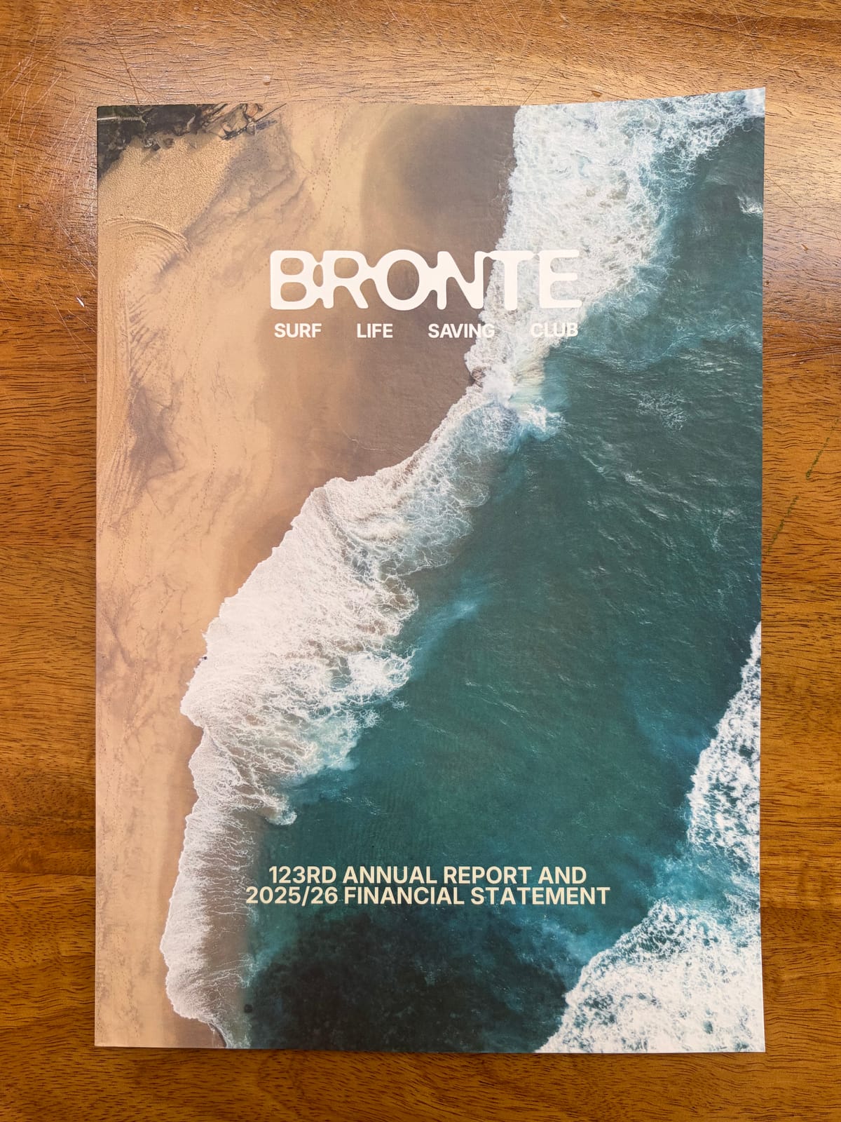 Bronte Surf Life Saving Club's 123rd Annual Report and 2025/26 Financial Statement, photographed from above on a wooden table
