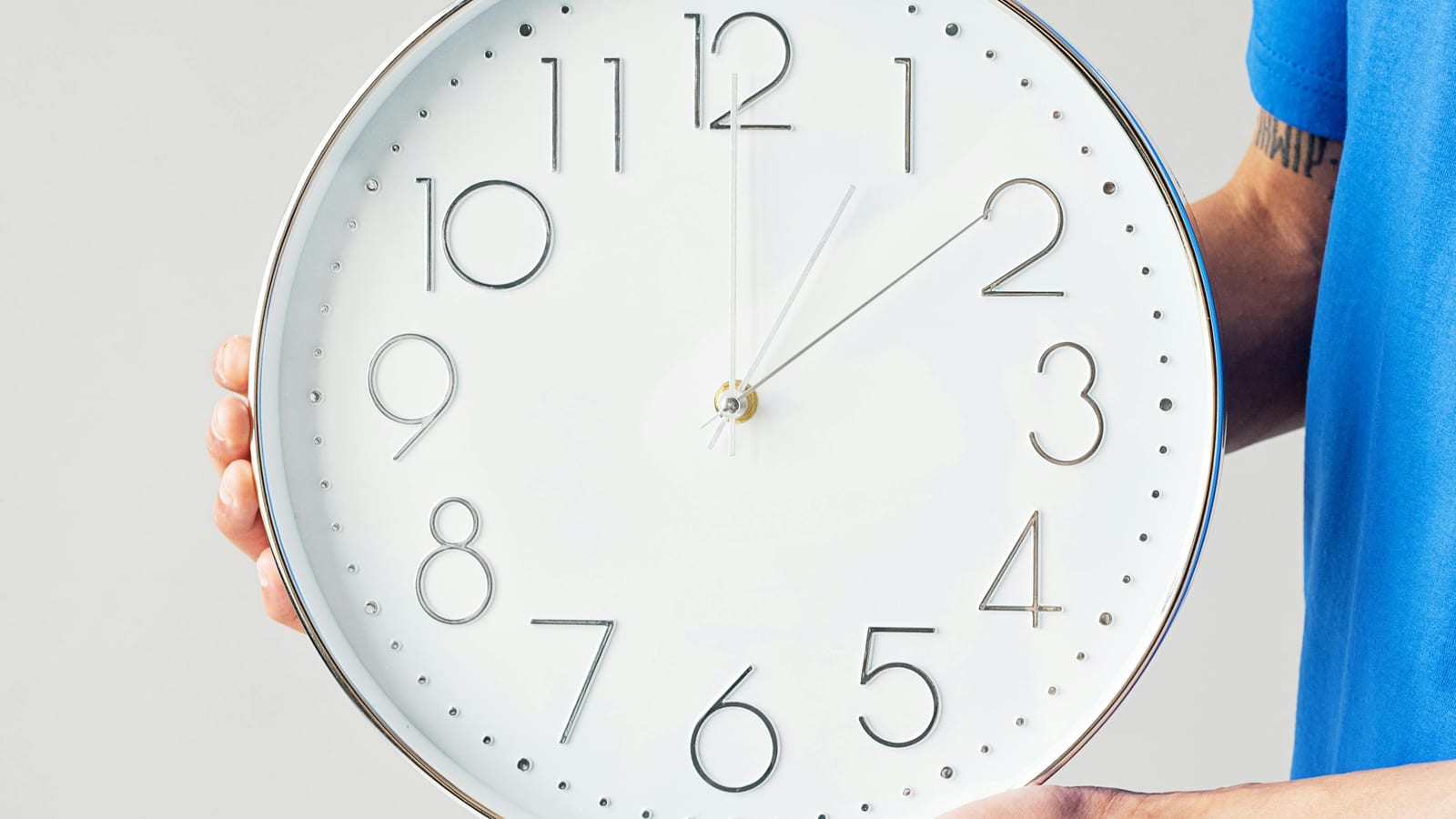 A volunteer in a blue shirt holding a large wall clock