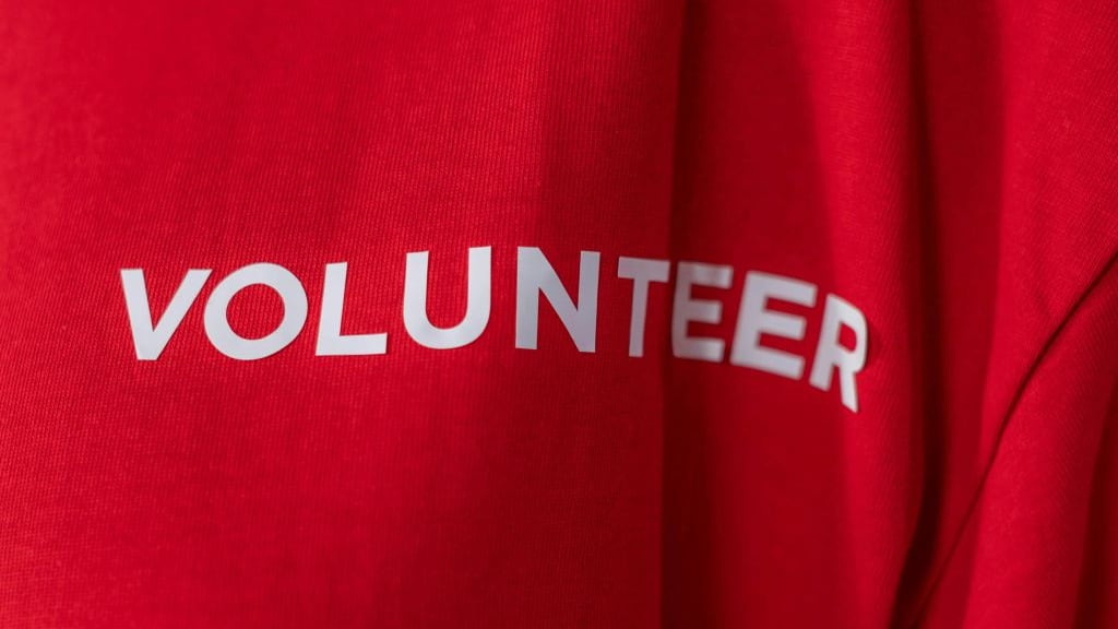 The back of a red long-sleeved shirt with VOLUNTEER printed across the shoulders in white